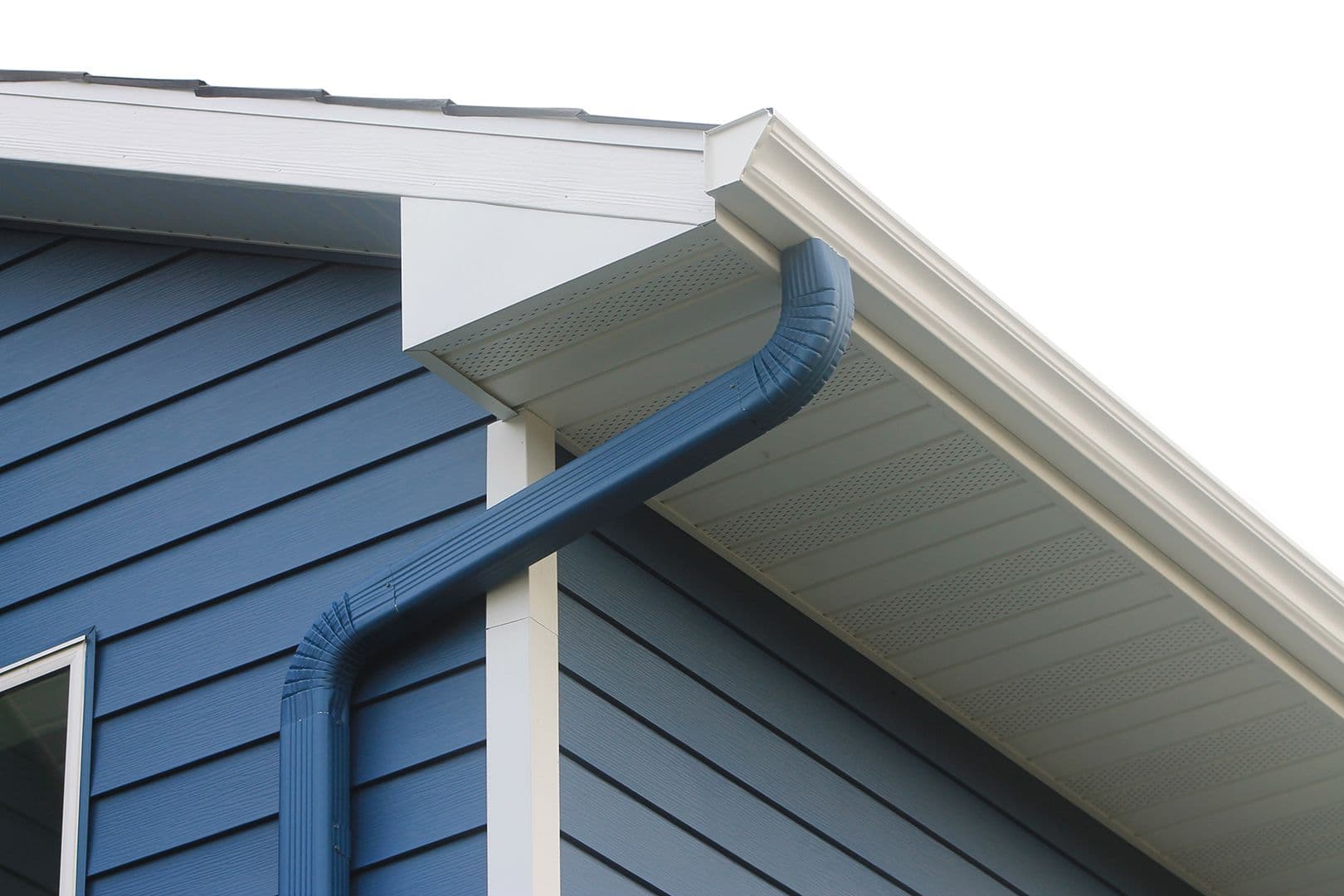 Blue downspout and gutters installed on blue vinyl siding with white trim and soffit at roofline