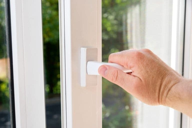 Hand opening white window handle to open patio door or window
