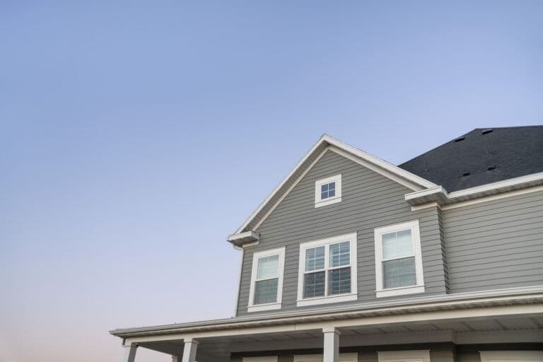 Two-story house with gray siding, white trim, dark roof, and front-facing gable with small window above large double windows