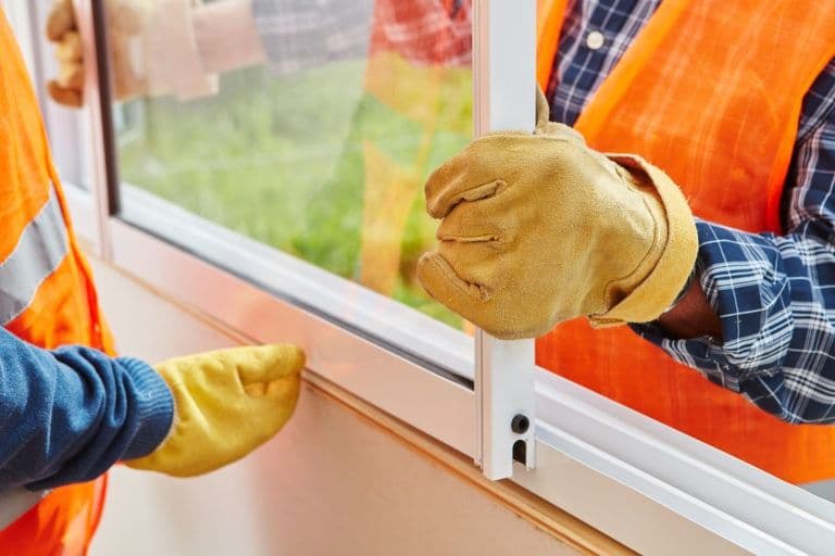 Worker installing weatherstripping on a window frame to improve home energy efficiency