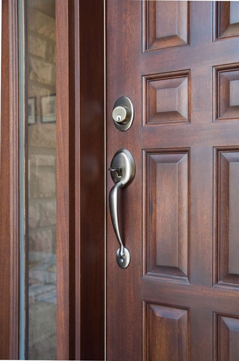 Dark wood front door with raised panel design, silver handle and deadbolt lock
