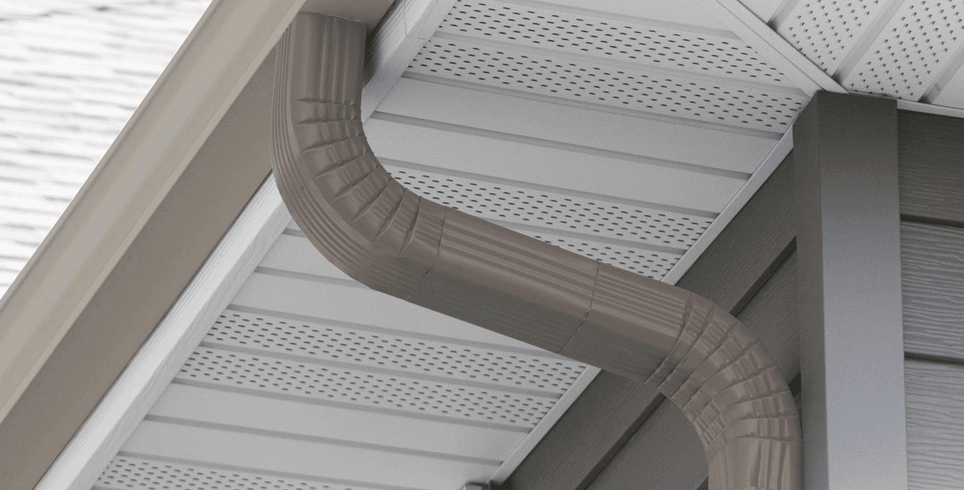 Downspout and gutter system installed under soffit and perforated fascia on residential roof overhang